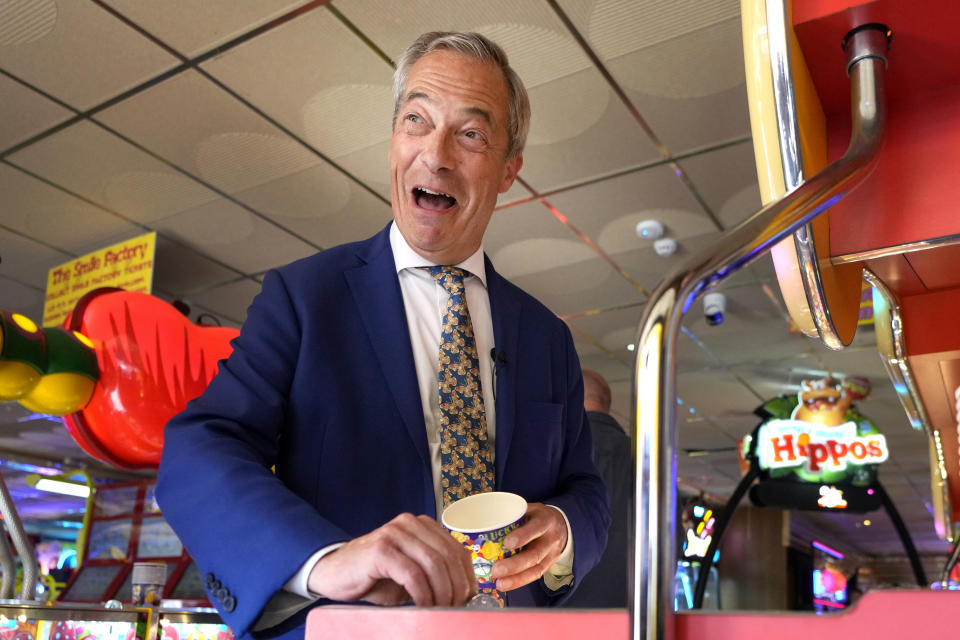 FILE - Britain's Nigel Farage, Reform UK party leader plays on a game in an amusement arcade holds out some coins whilst spending time with supporters in Clacton-On-Sea, Essex, England Friday, June 21, 2024. The United Kingdom will hold its first national election in almost five years on Thursday, with opinion polls suggesting that Prime Minister Rishi Sunak’s Conservative Party will be punished for failing to deliver on promises made during 14 years in power. (AP Photo/Kirsty Wigglesworth, File)