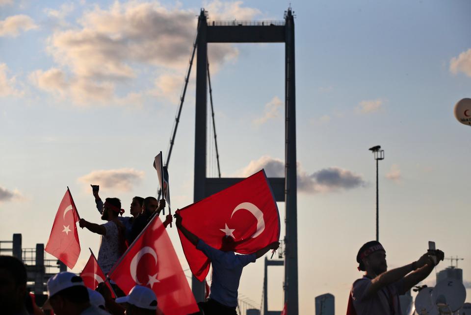 People wave Turkish flags near the July 15 Martyr's bridge on a "National Unity March - Credit: Lefteris Pitarakis/AP