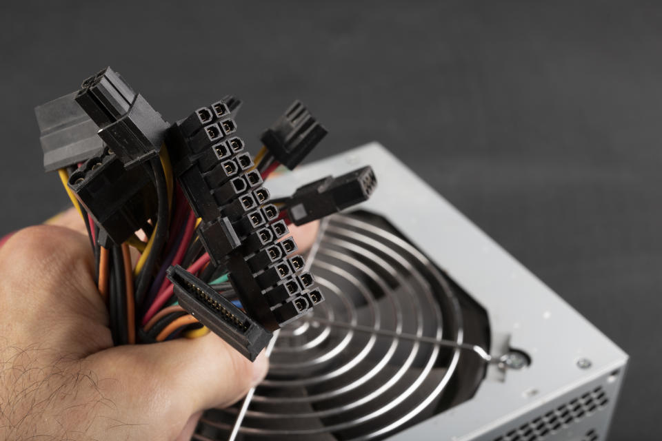 Hand held plugs for powering PC components. Components of the computer power supply. Dark background.