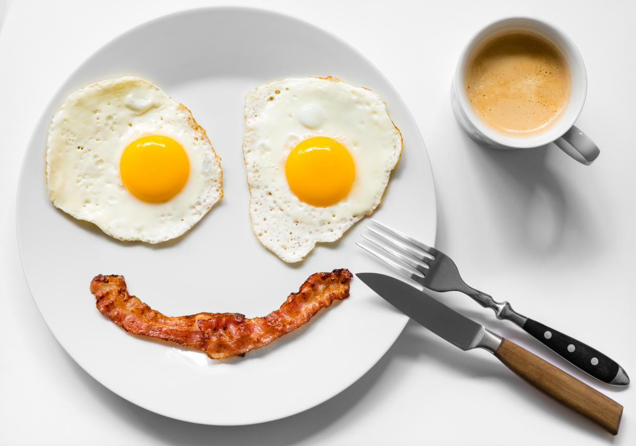 Smiling and positive face made from fried eggs and bacon on plate