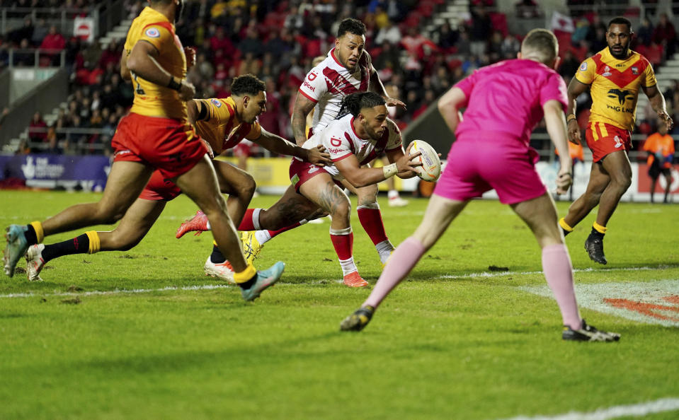 Tonga's Keaon Koloamatangi, centre, scores a try, during the Rugby League World Cup group D match between Tonga and Papua New Guinea at Totally Wicked Stadium, in St Helens, Merseyside, England, Tuesday, Oct. 18, 2022. (Martin Rickett/PA via AP)