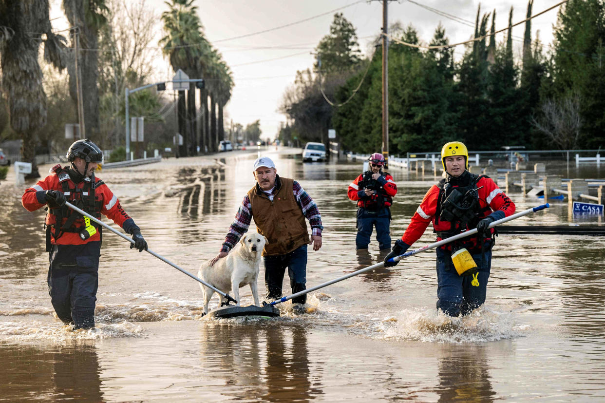 San Diego firefighters help Humberto Maciel rescue his dog  from his flooded home in Merced, Calif., on Jan. 10, 2023. (Josh Edelson/AFP via Getty Images)