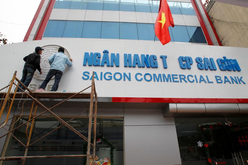 FILE PHOTO: Workers decorate the sign of the Saigon Commercial Bank at a place which formerly operated by First Bank, in Hanoi