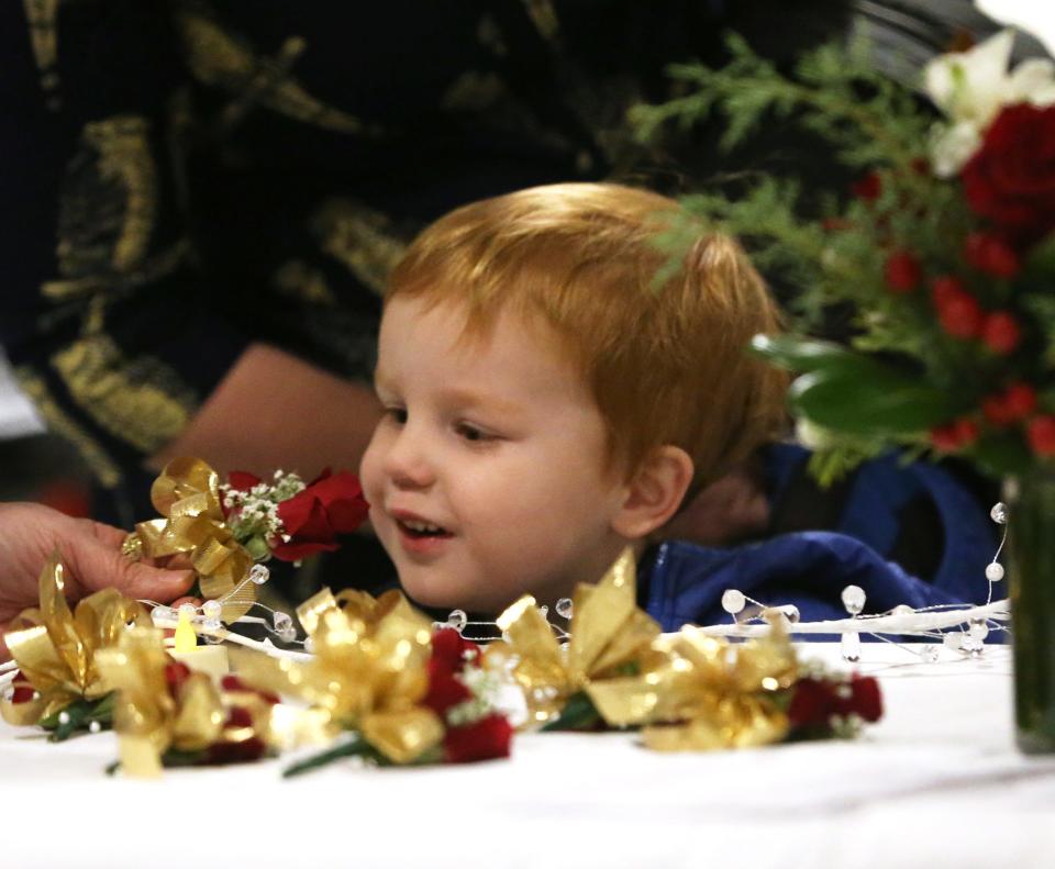 Griffin Matto gets to smell the scent of a rose as his father, Byron Matto gets a corsage before getting sworn in as a School Board member at Portsmouth City Hall Tuesday, Jan. 2, 2024.
