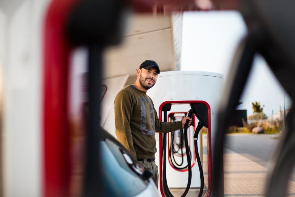 A person charges an electric vehicle at a charging station. 