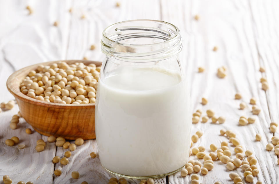 Non-dairy alternative Soy milk or yogurt in mason jar on white wooden table with soybeans in bowl aside