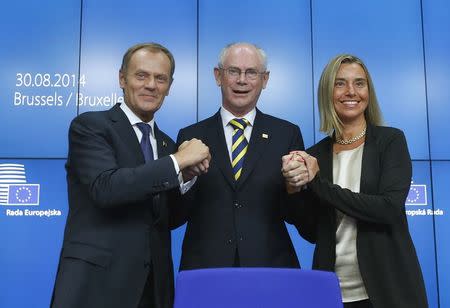 Newly elected European Council President Donald Tusk (L) of Poland and newly elected European High Representative for Foreign Affairs Federica Mogherini (R) of Italy are congratulated by outgoing European Council President Herman Van Rompuy during an EU summit in Brussels August 30, 2014. REUTERS/Yves Herman