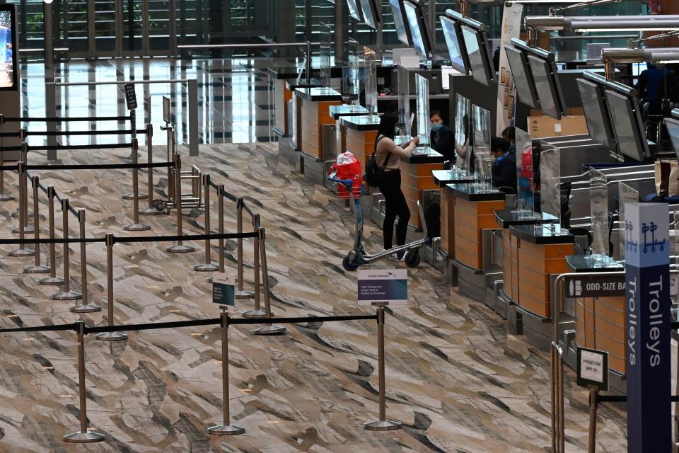 A passenger checks in at the departure hall counter of Changi International Airport terminal in Singapore on January 14, 2021. (Photo by Roslan RAHMAN / AFP) (Photo by ROSLAN RAHMAN/AFP via Getty Images)