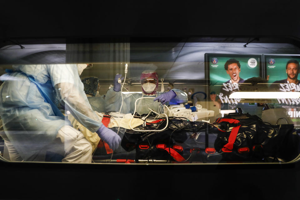 Medical staff place a patient infected with the COVID-19 virus onto a train at the Gare d'Austerlitz train station, Paris, Wednesday April 1, 2020. France is evacuating 36 patients infected with the coronavirus from the Paris region onboard two medicalized high-speed TGV trains. The patients, all treated in intensive care units (ICU), are being transferred to several hospitals in Brittany, as western France is less impacted by the epidemic. The new coronavirus causes mild or moderate symptoms for most people, but for some, especially older adults and people with existing health problems, it can cause more severe illness or death. (Thomas Samson/Pool via AP)