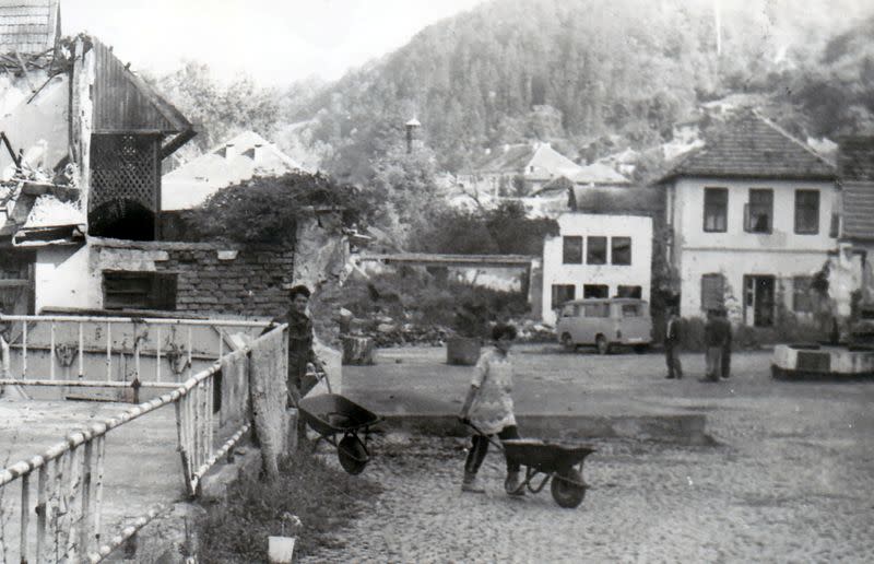 People push wheelbarrows in an old area destroyed by the Bosnian War in Maglaj