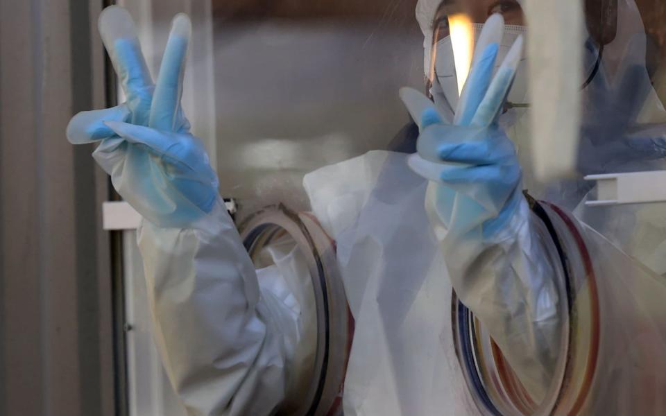 A medical worker gestures at a makeshift clinic for coronavirus tests in front of Seoul Station - YONHAP/EPA-EFE/Shutterstock