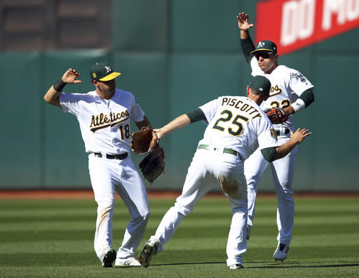 Oakland Athletics outfielders, from left to right, Chad Pinder, Stephen Piscotty and Ramon Laureano celebrate their win over the Texas Rangers at the end of a baseball game Sunday, Sept. 9, 2018, in Oakland, Calif. (AP Photo/Ben Margot)