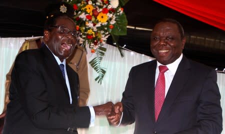 FILE PHOTO: Zimbabwe President Robert Mugabe jokes with Prime Minister Morgan Tsvangirai after signing Zimbabwe's new constitution into law in the capital Harare