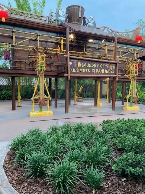 Mr. Ping's Noodle Kaboodle restaurant entrance with decorative sign featuring a bird mascot holding noodles above and wooden façade in the background