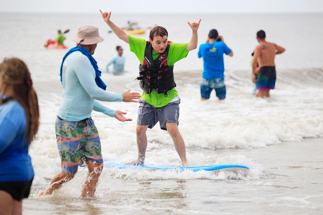 Alexander Arceneaux, 16, gives a double hang loose sign as he surfs at the 16th annual HEAL Foundation surf camp at Neptune Beach on June 13. The Helping Enrich Autistic Lives Foundation was established to educate and fund services and programs for those affected by autism in the community. It is one of more than 8,000 nonprofit organizations active in the Jacksonville area.