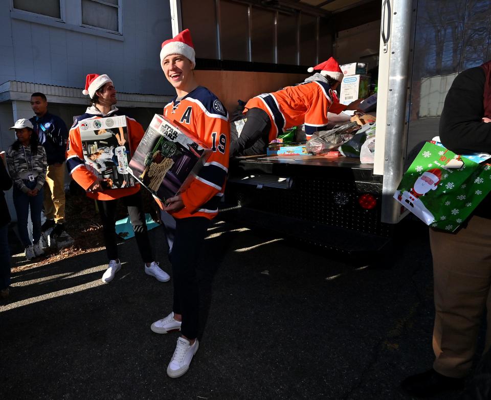 Worcester Railers players Blade Jenkins, center, Zach White, right, and Anthony Repaci drop off toys and teddy bears collected for Friendly House of Worcester from Saturday's game at the DCU Center.