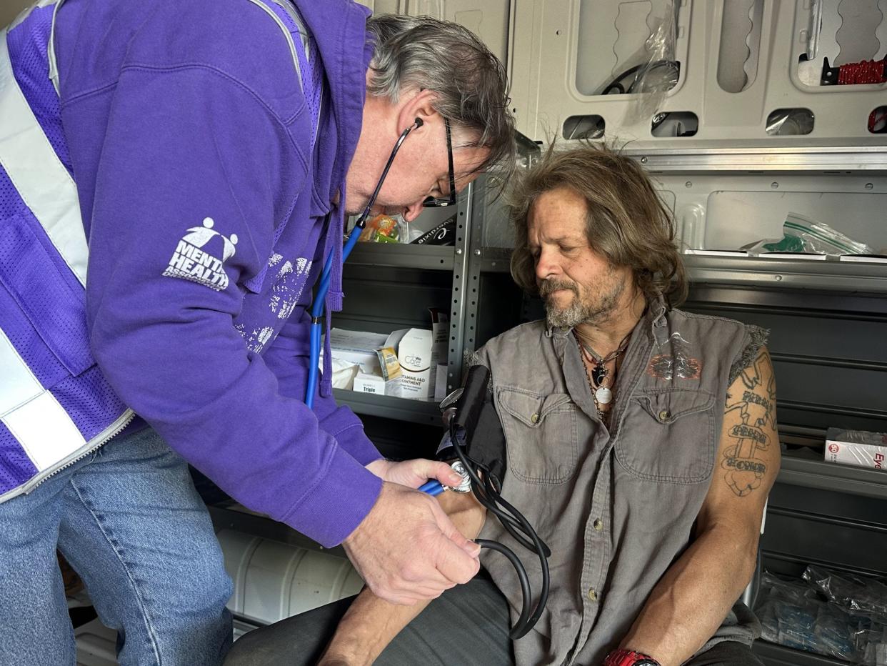 Tim Chandler, a licensed practical nurse who works with the Mental Health Association Oklahoma Street Medicine Outreach team checks Robert Hairell's blood pressure during a visit to a large homeless encampment in Oklahoma City.