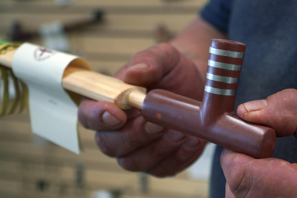 Travis Erickson holds a handmade pipe that he carved and crafted from pipestone, which is sold in his shops, on Wednesday, May 3, 2023, in Pipestone, Minn. Only Native Americans enrolled in a federally recognized tribe are permitted to quarry the sacred pipestone at the Pipestone National Monument. (AP Photo/Jessie Wardarski)