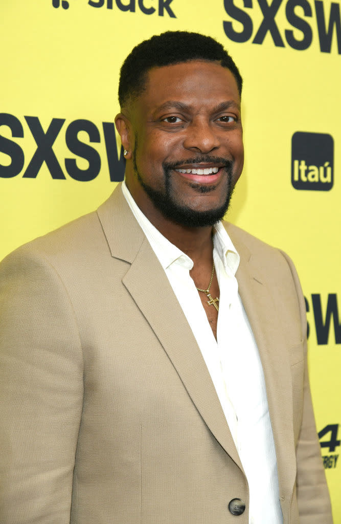 Chris smiling and wearing a blazer and shirt at a media event