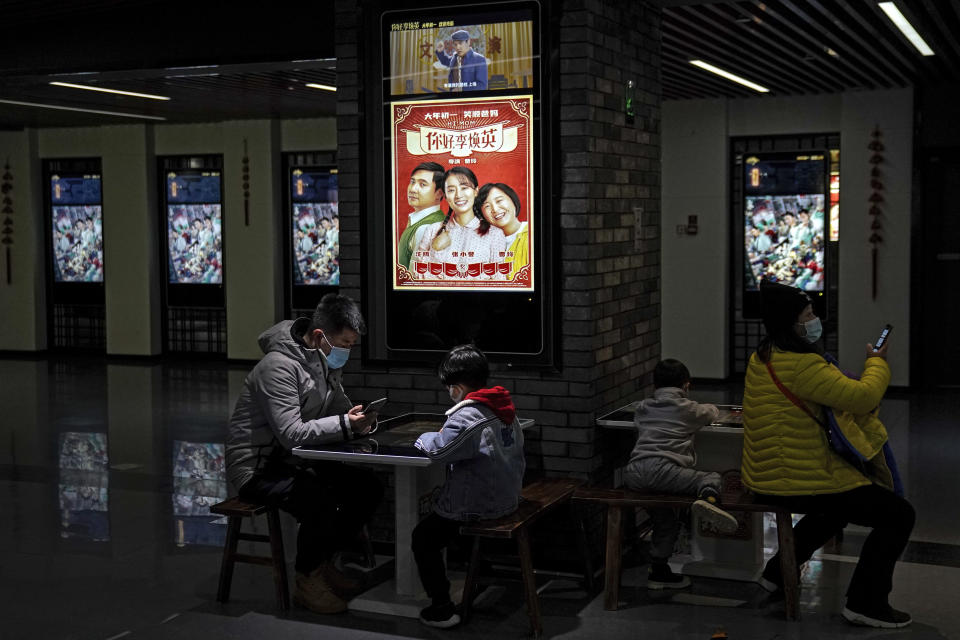 People wearing face masks to help curb the spread of the coronavirus wait for their movies at Poly Cinema in Beijing on Thursday, Feb. 25, 2021. With coronavirus well under control in China and cinemas running at half capacity, moviegoers are smashing China's box office records, setting a new high mark for ticket sales in February, with domestic productions far outpacing their Hollywood competitors.(AP Photo/Andy Wong)