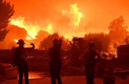 Firefighters battle a wind-driven wildfire called the Saddle Ridge fire in the early morning hours Friday in Porter Ranch