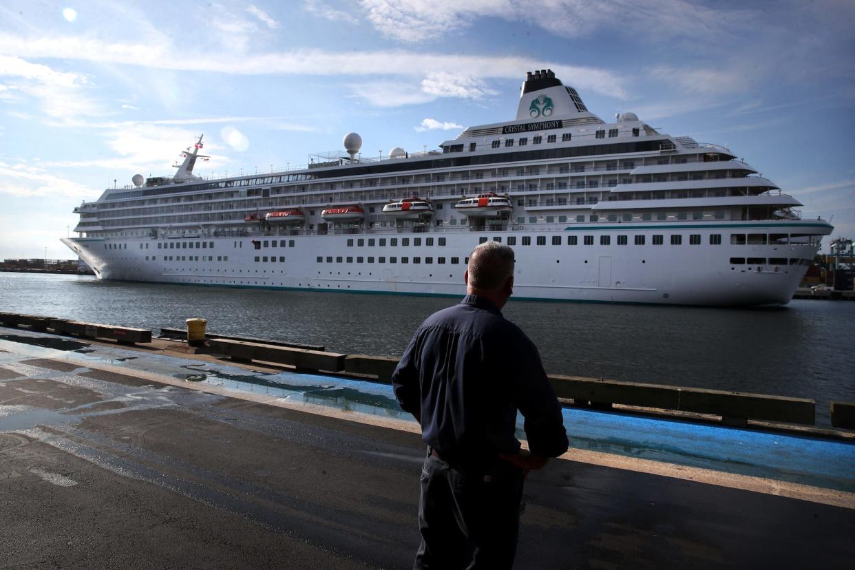 A pedestrian watches as the Crystal Symphony cruise ship arrives at Flynn Cruiseport in Boston, MA on August 18, 2021.