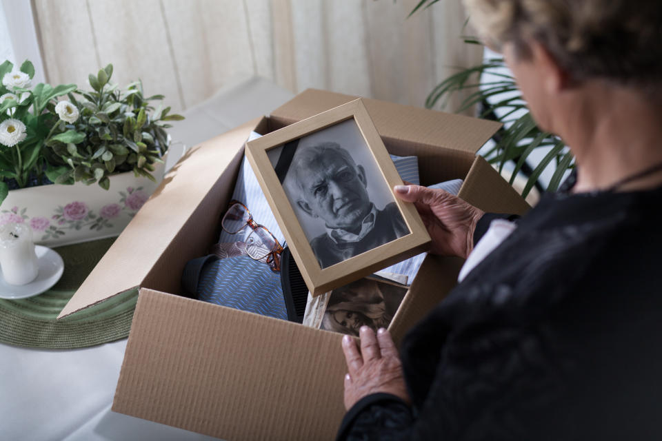 Woman is packing things of her dead husband into a box 