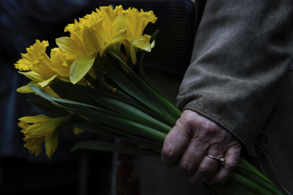 A woman holds yellow tulips during personal unofficial observances marking the 80th anniversary of the Warsaw Ghetto Uprising in Warsaw, Poland, Wednesday, April 19, 2023. (AP Photo/Michal Dyjuk)