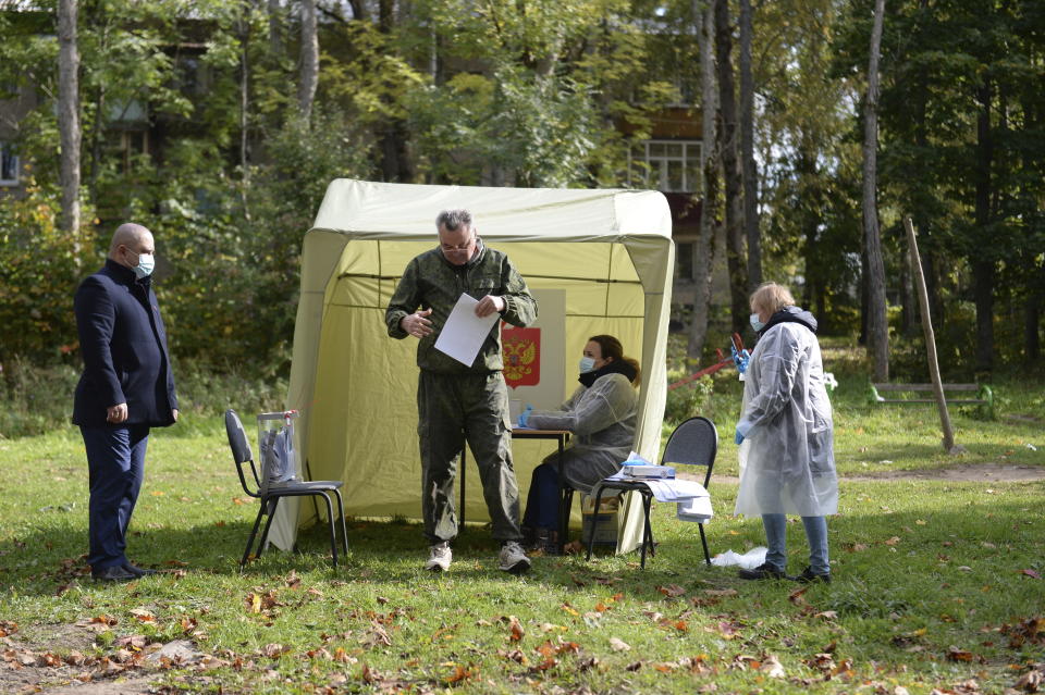 A voter prepares to casts his ballot at a mobile polling station in front the Church of the Epiphany during the Parliamentary elections in Sharapovo village, Moscow region, Russia, Saturday, Sept. 18, 2021. The Communist Party and independent observers have reported an array of alleged violations in the voting that is widely expected to keep the dominant United Russia party's majority in parliament. (AP Photo/Denis Kaminev)