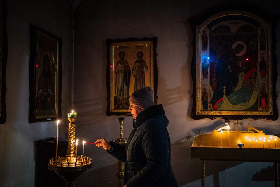 A woman lights a candle in St Andrew’s Church in Bucha, near Kyiv on Friday (AFP via Getty Images)