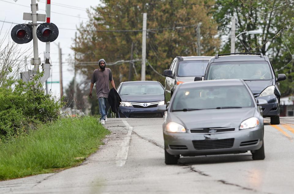 Vehicles navigate around a pedestrian who walks north on Girls School Road, south of the intersection with 10th Street, on Monday, May 3, 2021. A 3.8-mile stretch of Girls School Road, between Crawfordsville Road and Morris Street, will eventually undergo construction to become a "complete street," making it pedestrian, bike and car-friendly.