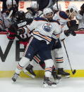 Edmonton Oilers defenseman Adam Larsson, right, and left wing Jujhar Khaira get the upper hand on Ottawa Senators' Clark Bishop along the boards during the third period of an NHL hockey game Wednesday, April 7, 2021, in Ottawa, Ontario. (Adrian Wyld/The Canadian Press via AP)