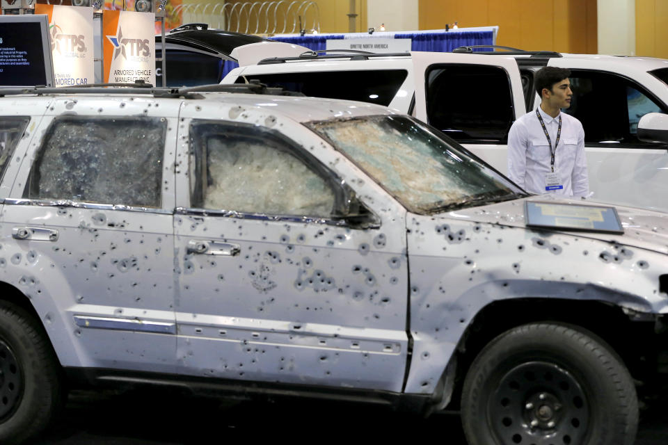 Patricio Canavati, of TPS Armoring stands between two vehicles that his company armored, one with over 1,800 bullet holes, and a newly armored SUV, at the 8th annual Border Security Expo, Tuesday, March 18, 2014 in Phoenix. The bullet riddled SUV saved the life of secretary of Public Security of the state of Michoacan, Mexico, Minerva Bautista Gomez in 2010. The two day event will feature panel discussions, sharing intelligence, and exhibitors displaying high-tech wares aimed at securing lucrative government contracts and private sales. (AP Photo/Matt York)