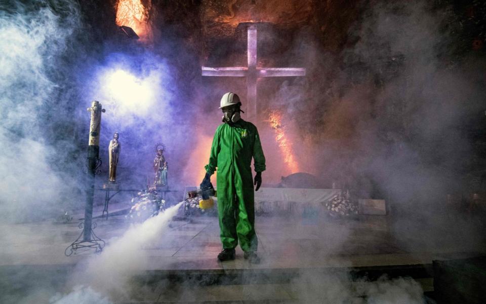 A worker disinfects the Salt Cathedral of Zipaquira, an underground church built into a salt mine, in Zipaquira, 45 km north of Bogota - JUAN BARRETO /AFP