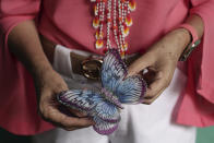A Salvadoran businesswoman, who is one of the applicants of a small refugee program that was shut down by President Donald Trump, holds a butterfly clothespin while standing inside her boutique in Santa Ana, El Salvador, Saturday, Aug. 22, 2020. The 56-year-old woman who also owns a small car sales business in western El Salvador, has been trying to join her husband in the U.S. through the Central American Minors program, or CAM, since 2016. (AP Photo/Salvador Melendez)