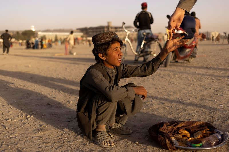 A boy sells food in a park in Kabul