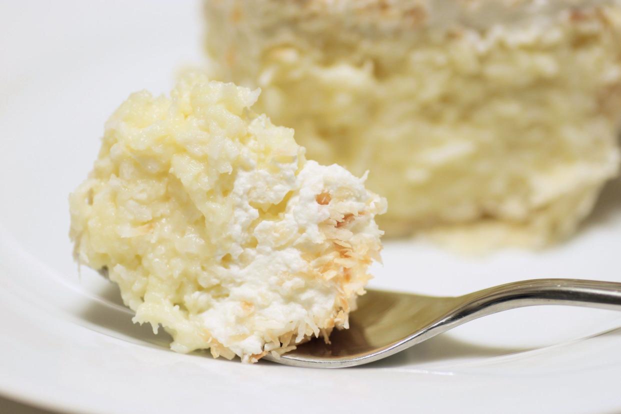 Slice of coconut cream pie on a white plate with a silver fork.