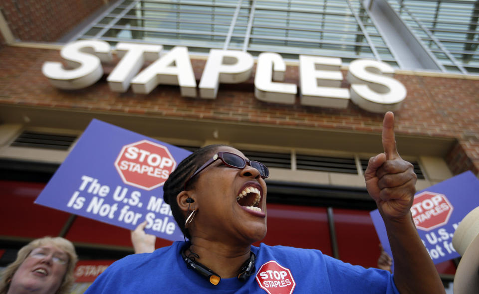 U.S. Post Office employee Detra Parker chants during a protest outside a Staples store, Thursday, April 24, 2014, in Atlanta. Thousands of postal workers picketed outside Staples stores nationwide Thursday to protest a pilot program that allows the office supply chain to handle U.S. mail. The American Postal Workers Union fears layoffs and post office closings and says that unlike retail workers, postal workers "have taken an oath to protect the sanctity of the mail." (AP Photo/David Goldman)