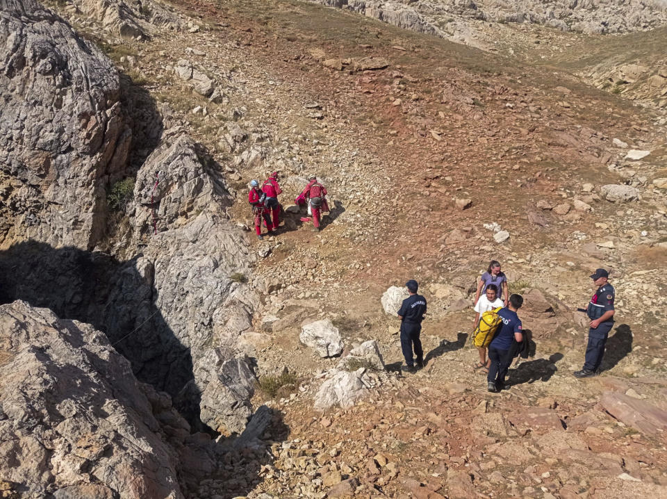 European Cave Rescue Association (ECRA) members and Turkish gendarmerie officers stand next to the entrance of Morca cave near Anamur, southern Turkey, Thursday, Sept. 7, 2023. Turkish and international cave rescue experts are working to save an American speleologist trapped at a depth of more than 1,000 meters (3,280 feet) in a cave in southern Turkey after he became ill. (Mithat Unal/Dia Images via AP)