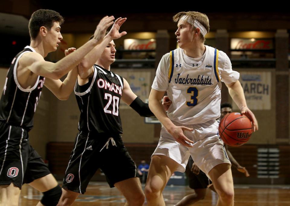 Baylor Scheierman #3 of the South Dakota State Jackrabbits looks for help while being guarded by Dylan Brougham #14 and Jadin Booth #20 of the Nebraska-Omaha Mavericks during the Summit League Basketball Tournament at the Sanford Pentagon in Sioux Falls, SD. (Photo by Dave Eggen/Inertia)