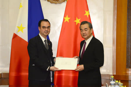 Philippine Foreign Affairs Secretary Alan Peter Cayetano, left, passes on a hand-written letter from President Rodrigo Duterte to Chinese President Xi Jinping during a meeting with Chinese Foreign Minster and State Counselor Wang Yi, right, at the Diaoyutai State Guesthouse in Beijing, China March 21, 2018. Parker Song/Pool via REUTERS