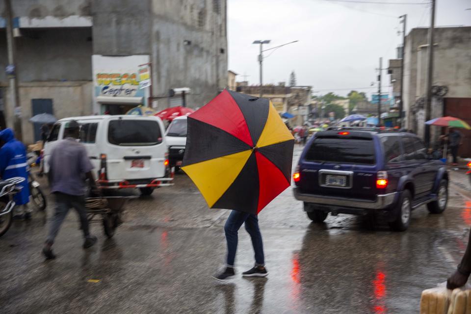 Pedestrians venture out into the rain brought by the outer bands of Hurricane Isaias in the Petionville district of Port-au-Prince, Haiti, early Friday, July 31, 2020. Isaias kept on a path early Friday toward the U.S. East Coast as it approached the Bahamas. (AP Photo/Dieu Nalio Chery)