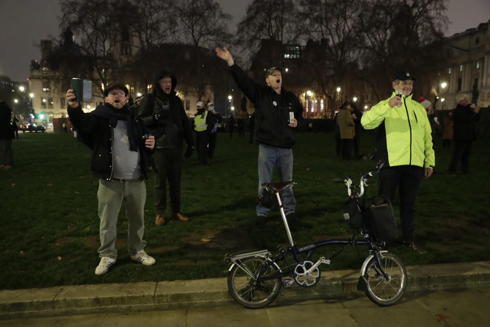 People raise a glass and celebrate in Parliament Square as the bell known as Big Ben strikes 2300, and Britain ends its transition period and formally leaves the European Union in London, Thursday, Dec. 31, 2020. Due to the coronavirus pandemic and the restrictions on gatherings people were moved on by police if they met in any number. (AP Photo/Matt Dunham)