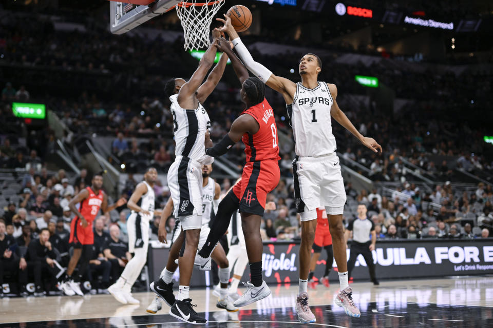 San Antonio Spurs' Victor Wembanyama (1) and Charles Bassey, left, tangle with Houston Rockets' Aaron Holiday, center, during the first half of a preseason NBA basketball game, Wednesday, Oct. 18, 2023, in San Antonio. (AP Photo/Darren Abate)