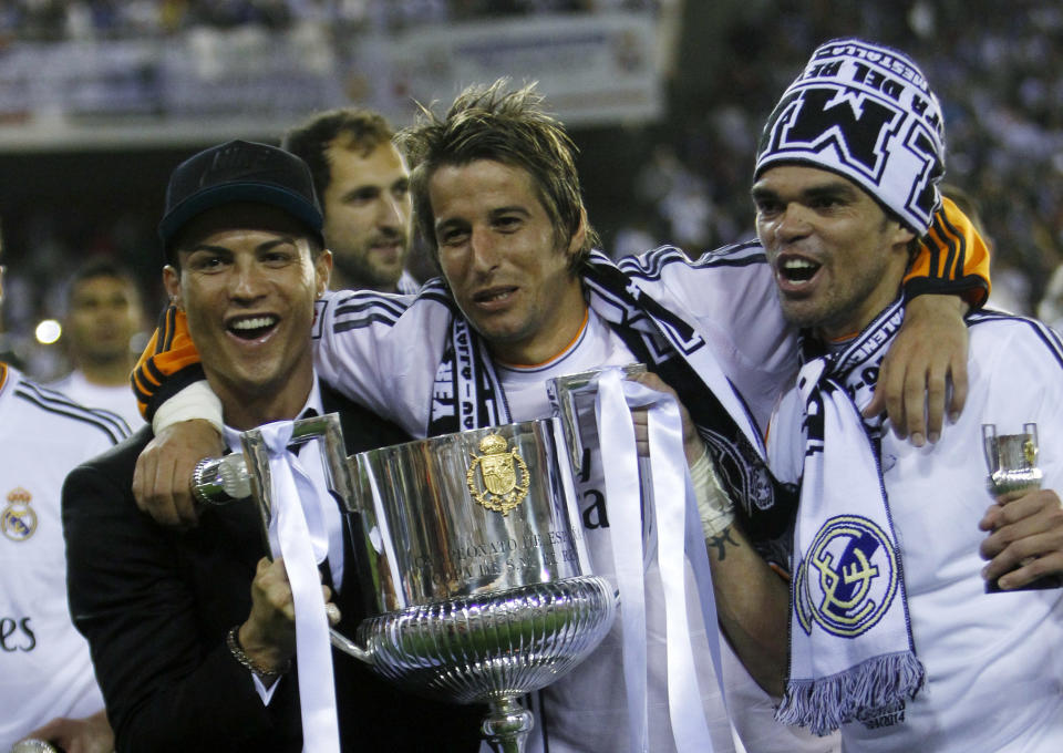 Real Madrid's Portuguese players Cristiano Ronaldo, left, Fabio Coentrao, centre and Pepe celebrate with the trophy after Real Madrid won the final of the Copa del Rey between FC Barcelona and Real Madrid at the Mestalla stadium in Valencia, Spain, Wednesday, April 16, 2014. (AP Photo/Alberto Saiz)
