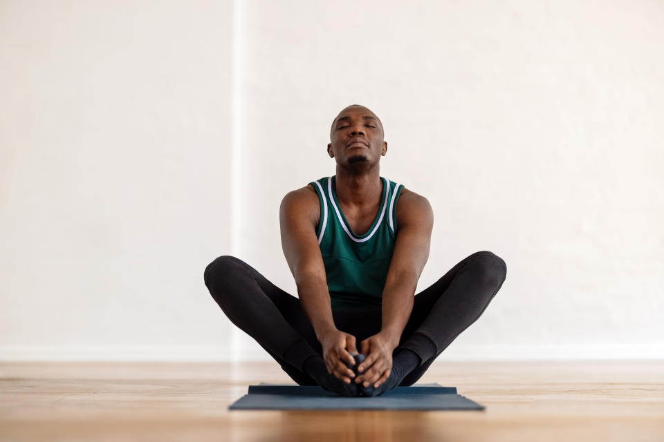 Man doing a yoga pose on a matt in studio looking space. (Getty Images)