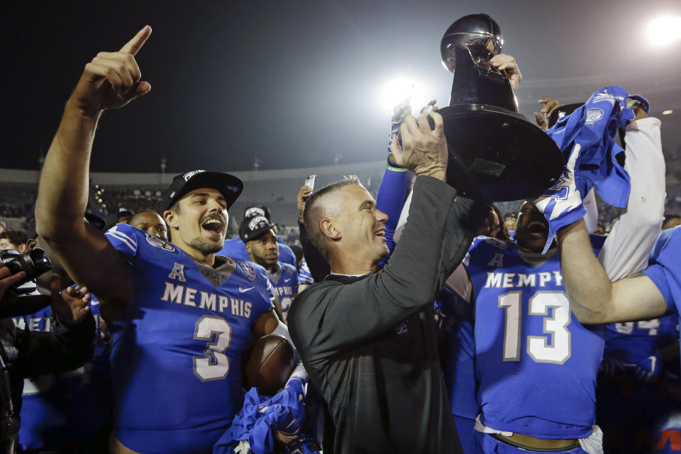Memphis quarterback Brady White (3) celebrates as head coach Mike Norvell, center, lifts the trophy after they defeated Cincinnati in an NCAA college football game for the American Athletic Conference championship Saturday, Dec. 7, 2019, in Memphis, Tenn. (AP Photo/Mark Humphrey)