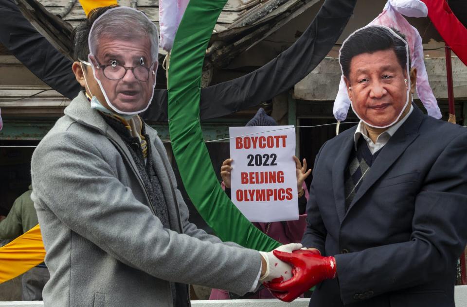 <span class="caption">Activists wearing masks of IOC President Thomas Bach and Chinese President Xi Jinping pose in front of the Olympic Rings during a street protest in India against the holding of the 2022 Beijing Winter Olympics.</span> <span class="attribution"><span class="source">(AP Photo/Ashwini Bhatia)</span></span>