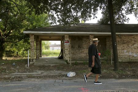 A man walks past an abandoned house in the Lower Ninth Ward neighborhood of New Orleans, Louisiana, July 31, 2015. REUTERS/Jonathan Bachman