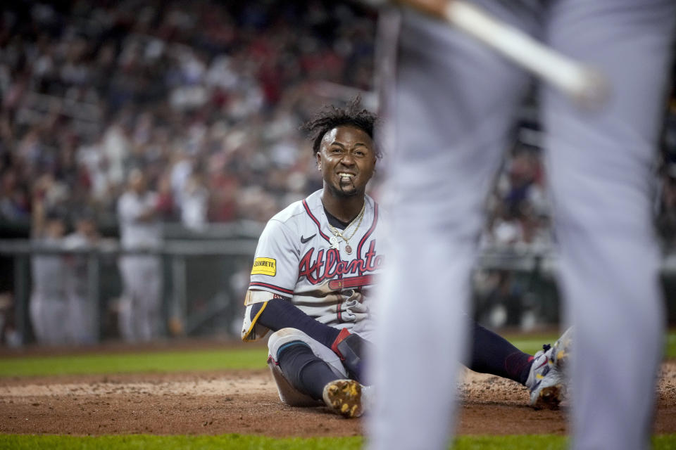 Atlanta Braves' Ozzie Albies sits in the dirt after sliding across home plate to score against the Washington Nationals during the third inning of a baseball game at Nationals Park, Thursday, Sept. 21, 2023, in Washington. (AP Photo/Andrew Harnik)